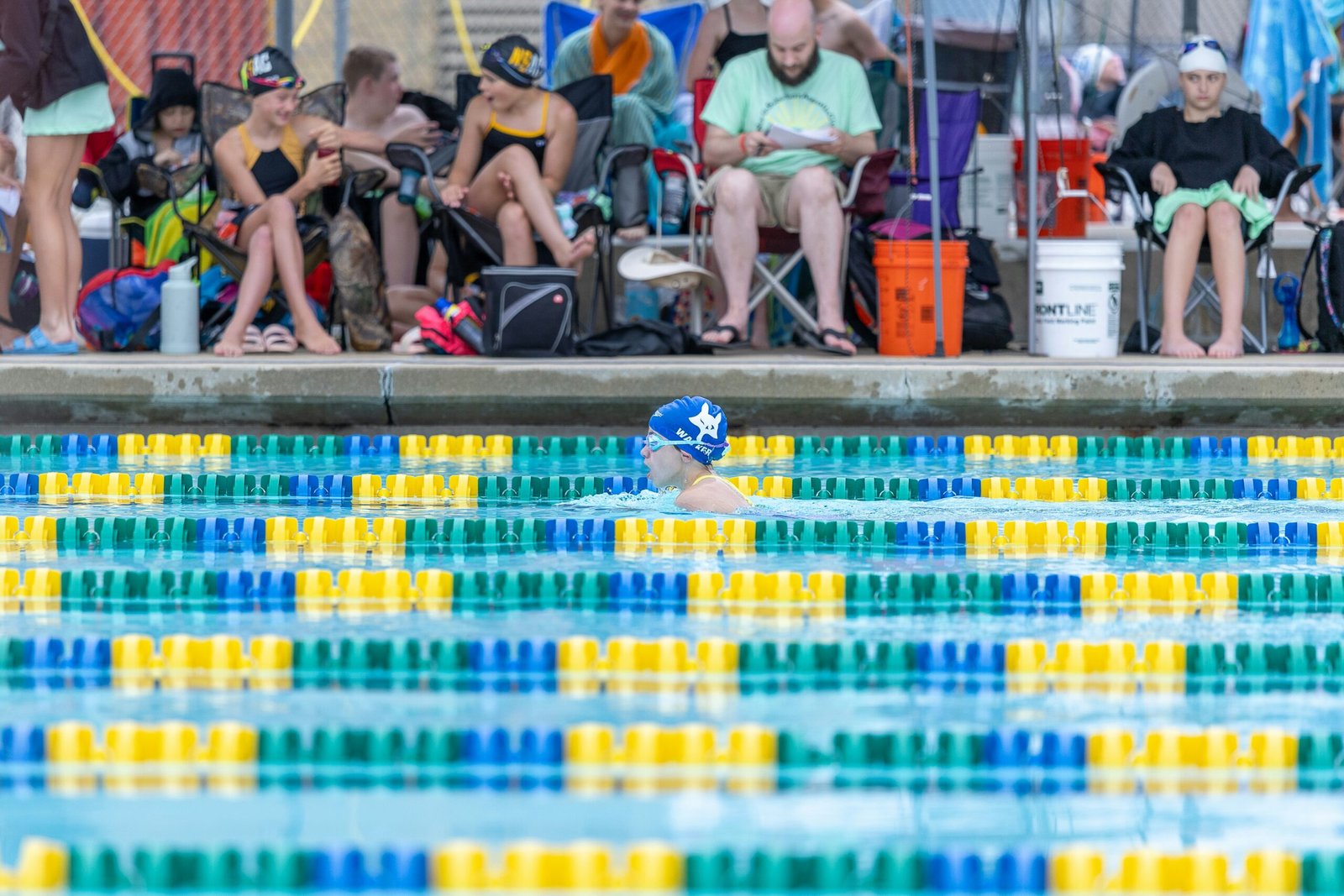 A group of people sitting on a bench next to a swimming pool